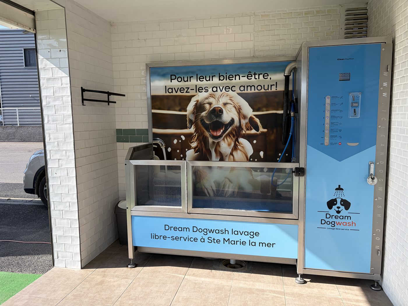 La cabine Dream Dog Wash à Sainte-Marie-la-Mer : bac de lavage en inox surélevé, panneau de commande à 7 programmes et visuel « Pour leur bien-être, lavez-les avec amour »